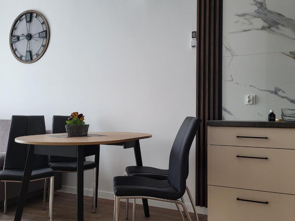 a dining room table with two chairs and a clock at Comfy apartment near the sea in G ski in Gąski