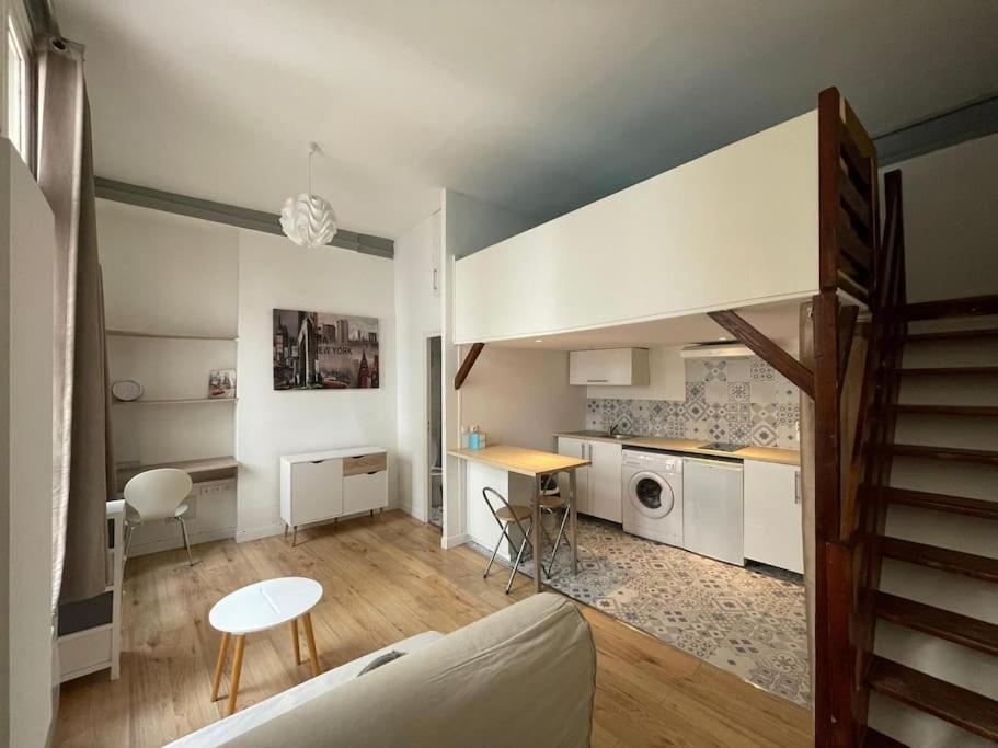 a living room with a staircase and a kitchen with a table at Studio Mezzanine N Dame in Versailles