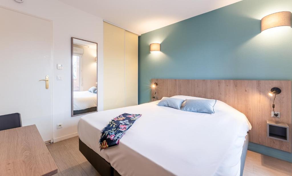 sypialnia z dużym białym łóżkiem i lustrem w obiekcie Zenitude Hôtel-Résidences Le Havre w Hawrze