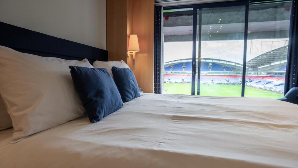 Schlafzimmer mit einem Bett und Blick auf ein Baseballspiel in der Unterkunft Bolton Stadium Hotel in Bolton