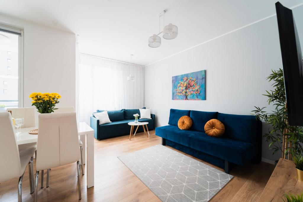 a living room with a blue couch and a table at Nice Apartment - Near Sky Tower - Private Parking in Wrocław