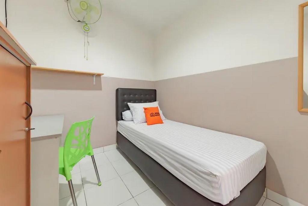 um pequeno quarto com uma cama e uma cadeira verde em KoolKost near BTC Fashion Mall 2 - Minimum Stay 30 Nights em Bandung