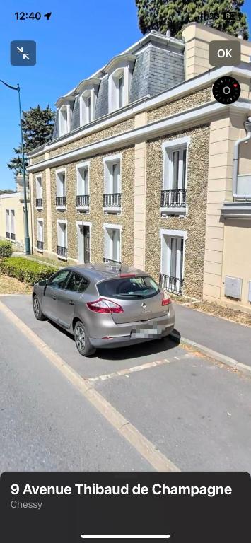 un coche aparcado en un aparcamiento frente a un edificio en Au cœur de Chessy, en Chessy