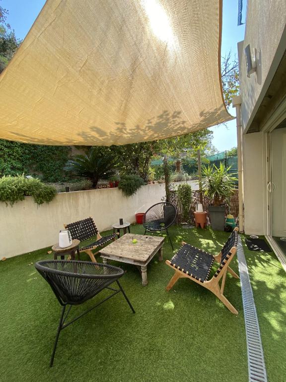 une terrasse avec des chaises, des tables et un grand parasol dans l'établissement Villa contemporaine - Prima Volta, à Nice