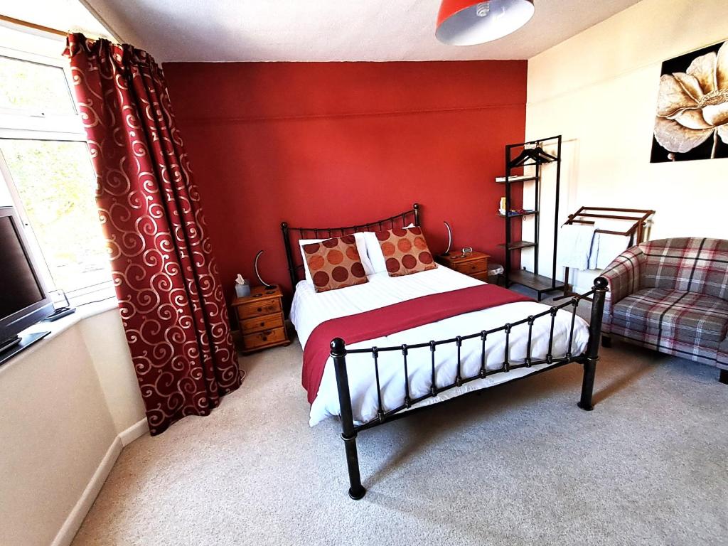 a bedroom with a bed and a red wall at Quiet comfortable Patcham studio Free parking Hallway shared with host in Brighton & Hove