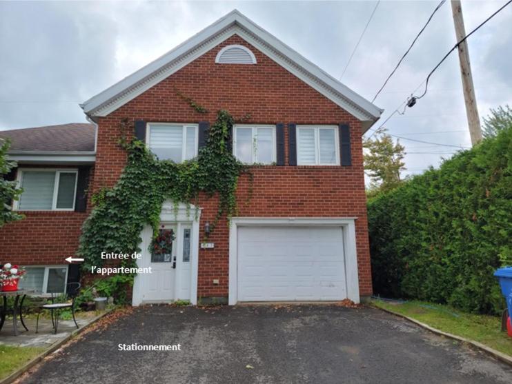 een rood bakstenen huis met een witte garage bij Le Calvados in Québec