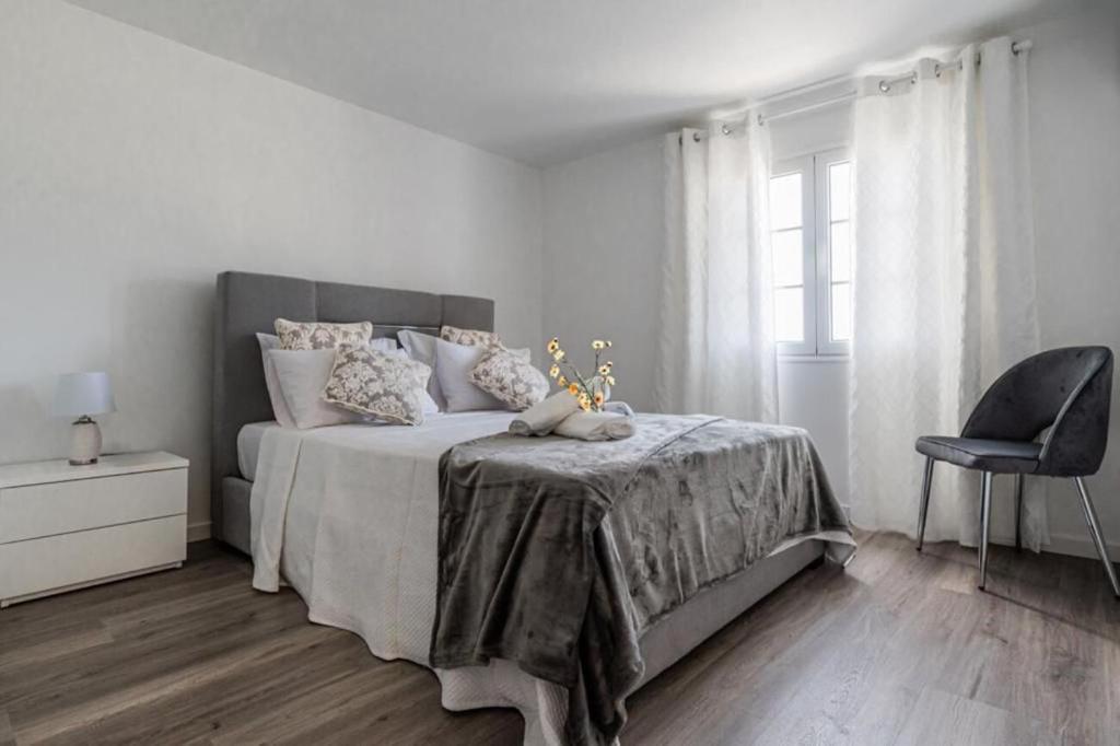 biała sypialnia z łóżkiem i krzesłem w obiekcie Sweet Home Madeira w mieście Camacha
