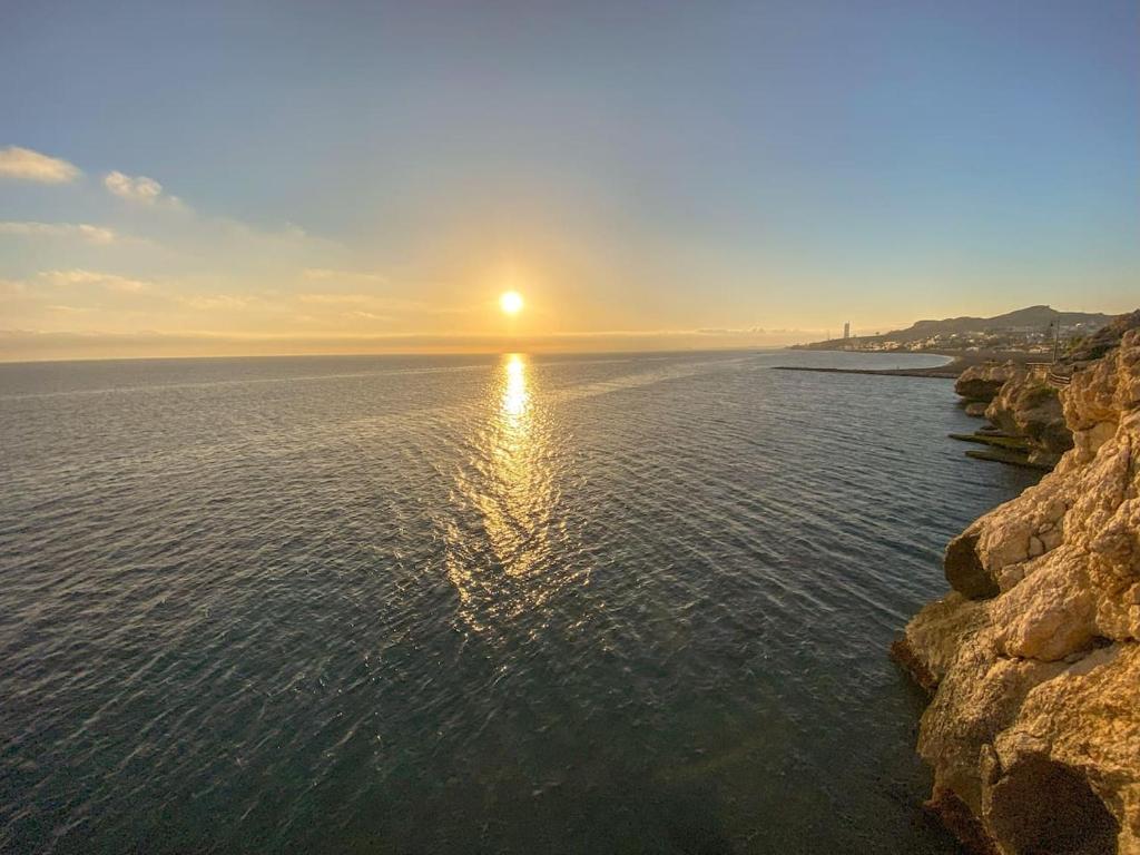 un coucher de soleil sur l'eau avec des rochers dans l'établissement Heerlijk penthouse, dakterras met prachtig zeezicht, kingsize bed, zwembad, 700m van strand, à Torre de Benagalbón