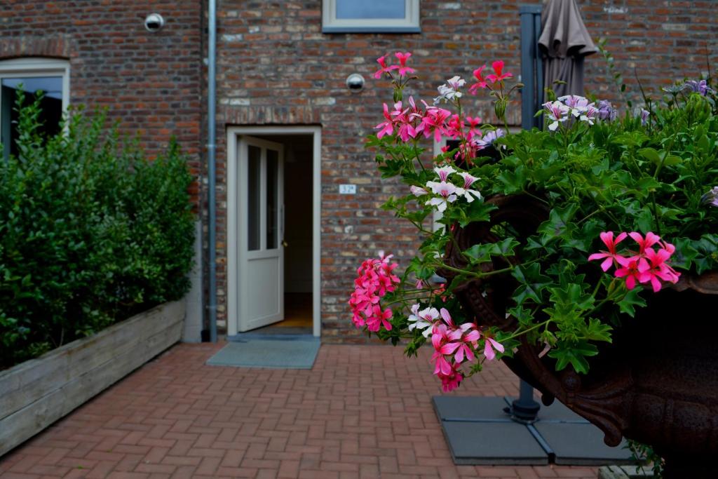 een deur naar een bakstenen gebouw met roze bloemen bij De Moolt Vakantiewoningen in Eckelrade
