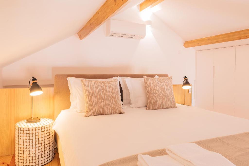 Un dormitorio con una gran cama blanca con almohadas. en ORM - Cedofeita I Apartment, en Oporto
