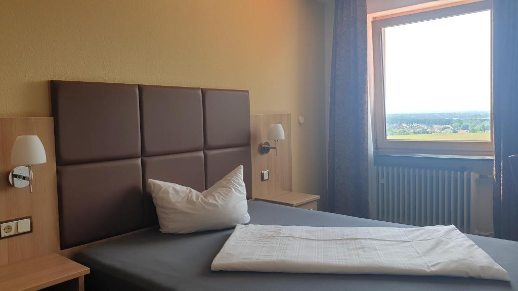 a bedroom with a bed with a pillow and a window at Restaurant und Hotel Alter Brunnen 