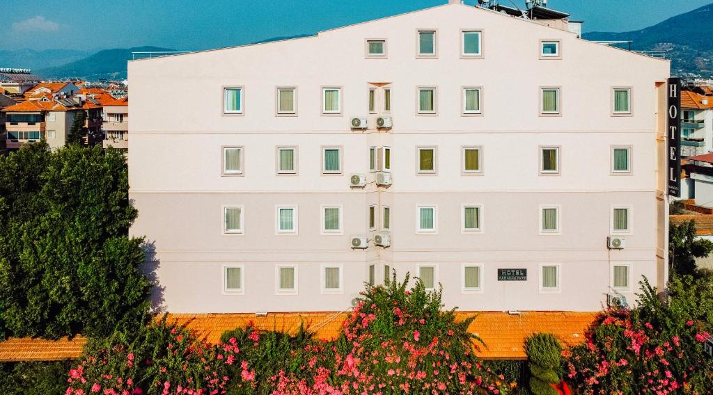 een wit gebouw op een heuvel met bloemen bij Karacan Park Hotel in Dalaman