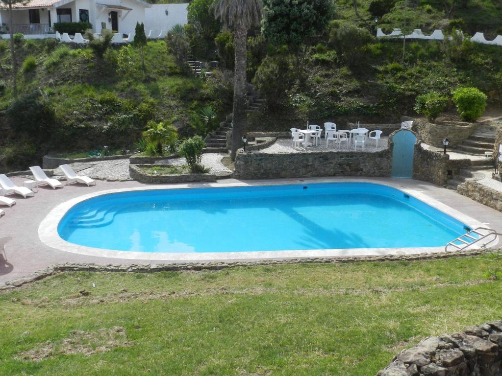 a swimming pool in a yard with chairs around it at Apartamentos Turísticos Clube Vale Leão in Figueira da Foz