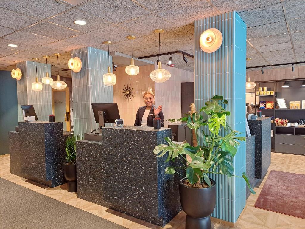 a woman standing behind a counter in a lobby at Original Sokos Hotel Vaakuna Pori in Pori