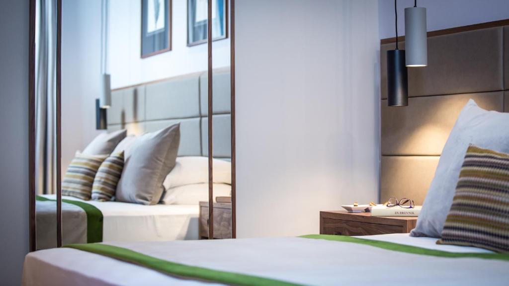 a hotel room with two beds and a mirror at Royal Neptun Hotel in Dubrovnik