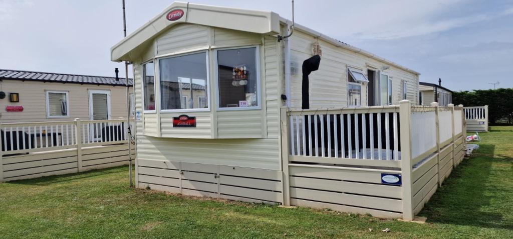 uma casa móvel com um alpendre e uma cerca em Ashdale By Sea em Whitstable