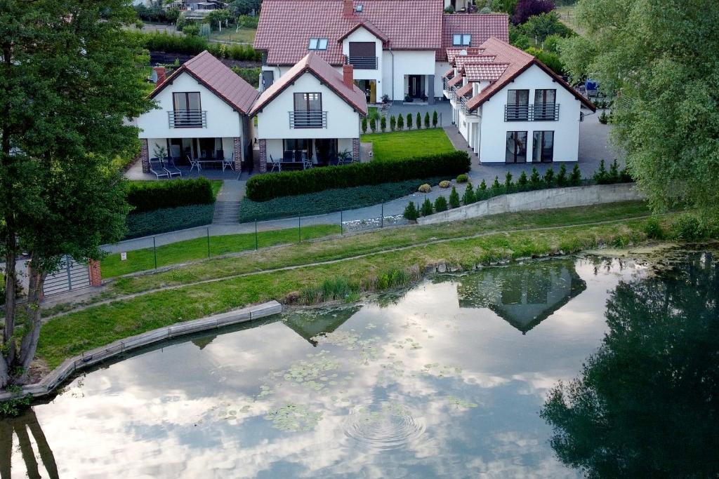 une maison avec un étang en face d'une maison dans l'établissement Trzy Wyspy Barlinek, à Barlinek