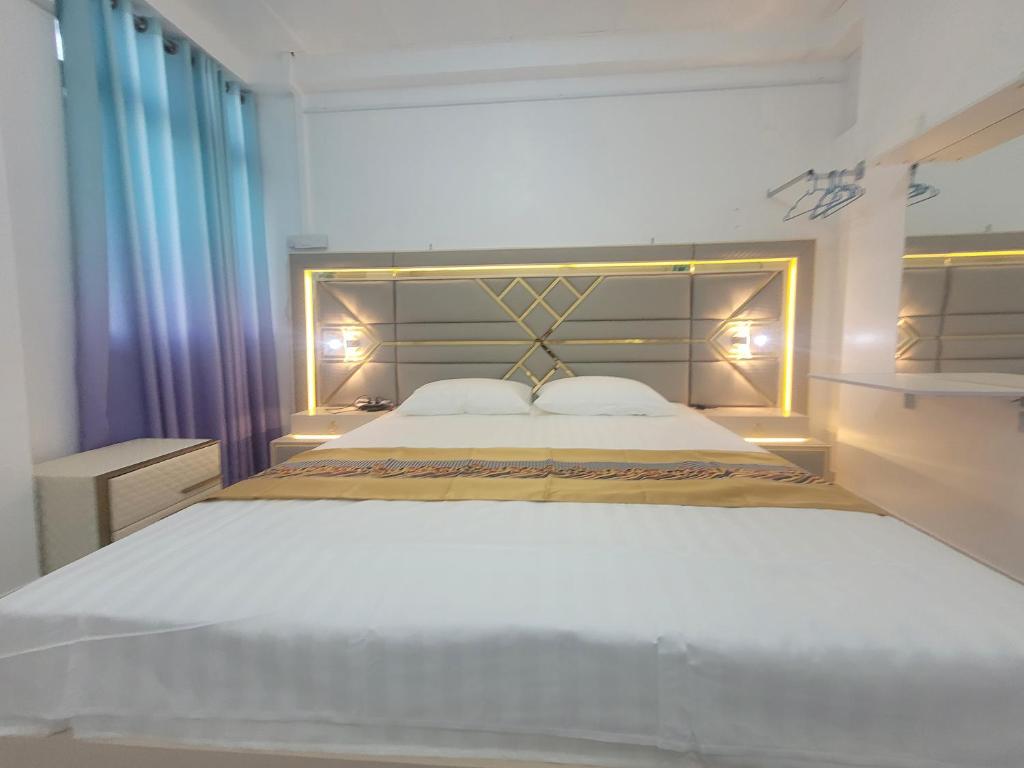 a bedroom with a large white bed with a headboard at Ontrack Travel in Male City