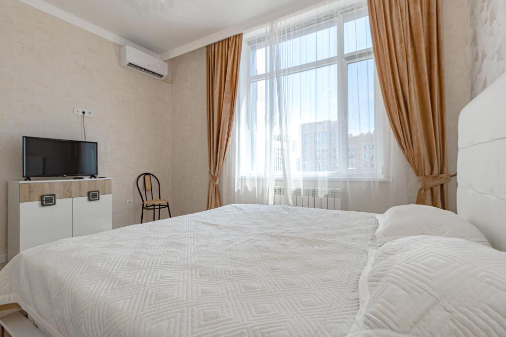 a bedroom with a bed and a tv and a window at Expo new life 2 in Prigorodnyy