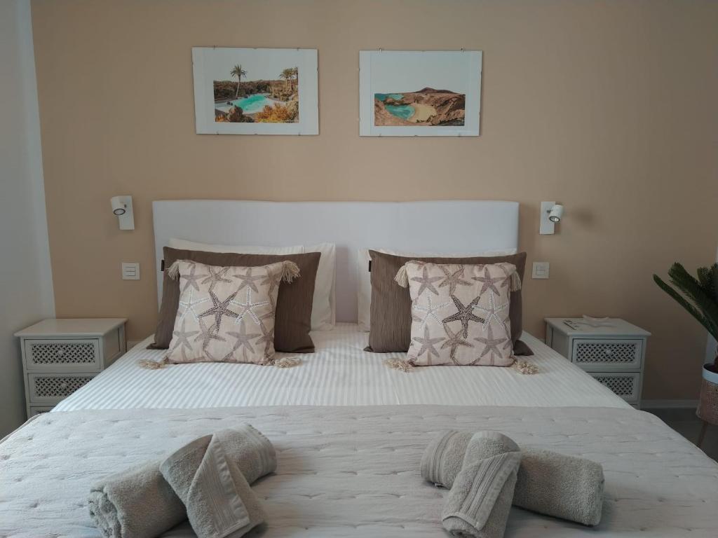 sypialnia z dużym białym łóżkiem z poduszkami w obiekcie Bungalow Paseo del Mar- PLAYA ROCA Residence sea front access - Free AC - Wifi w Costa Teguise