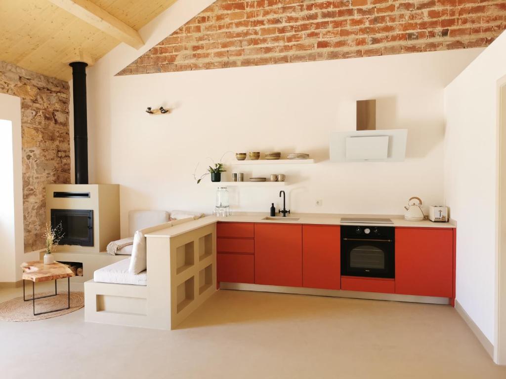 a kitchen with red cabinets and a brick wall at AL MAR Guesthouse in São Luis
