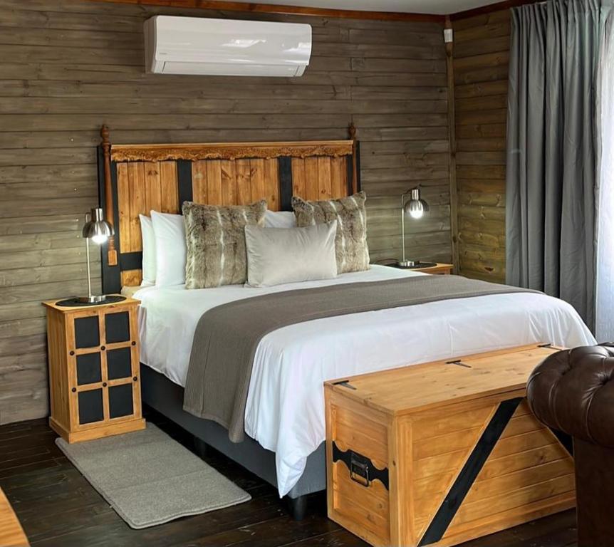 1 dormitorio con 1 cama grande y pared de madera en River Rock Lodge en Parys