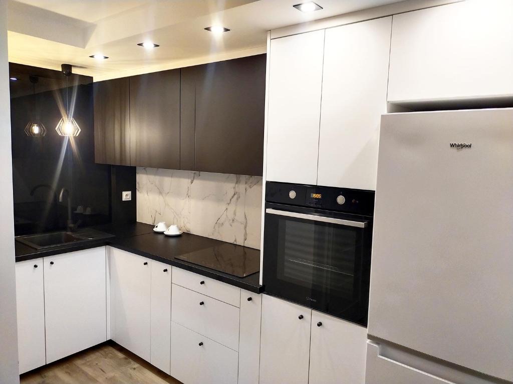 una cocina con armarios blancos y electrodomésticos negros en Apartament 11 Listopada, en Ostrołęka
