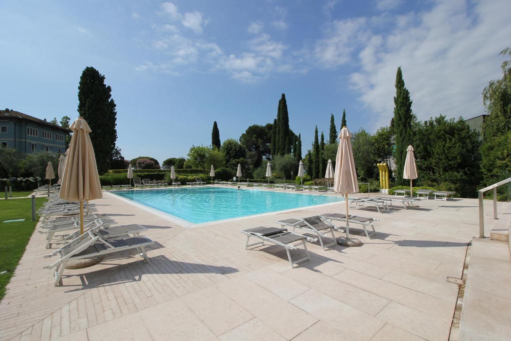 una piscina con sedie a sdraio e ombrelloni di Ginny House a Toscolano Maderno