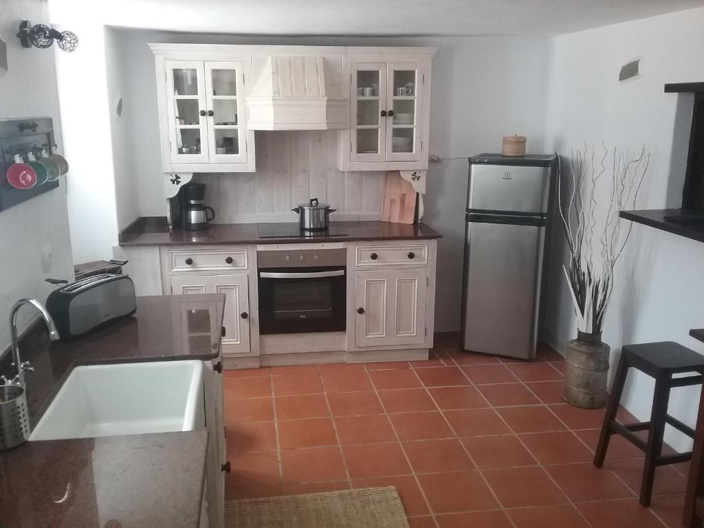 a kitchen with white cabinets and a sink and a refrigerator at Casa Rural "La Molina" in Máguez