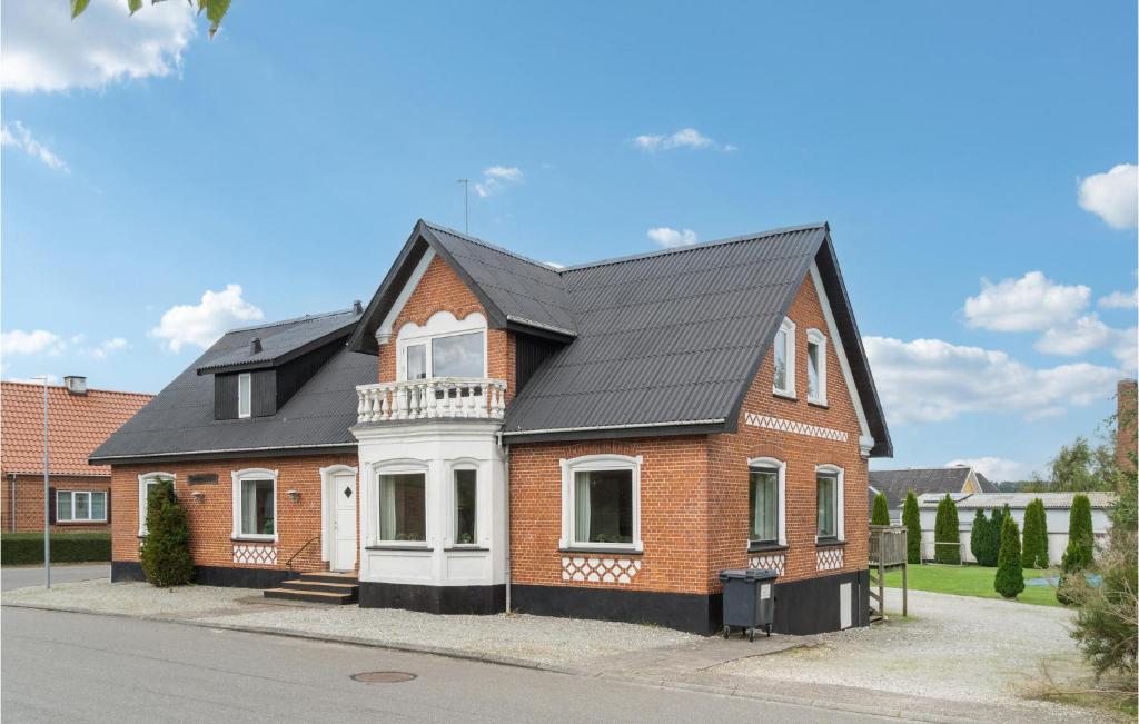 una casa de ladrillo rojo con techo negro en Beautiful Home In rum Djurs With Kitchen, en Nimtofte