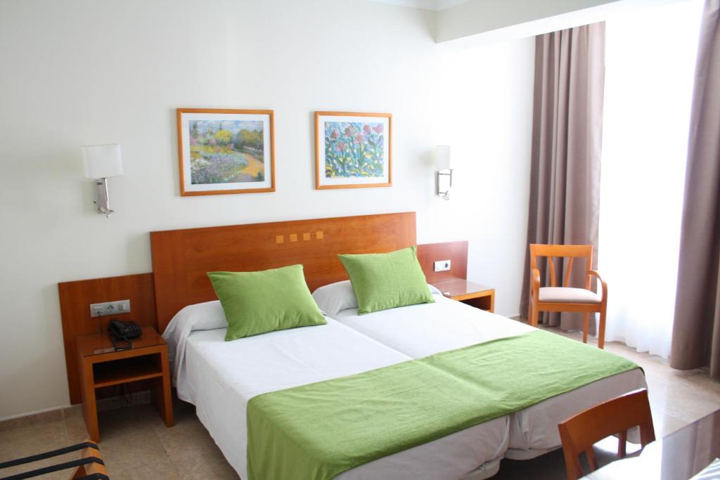 ein Schlafzimmer mit einem großen Bett und einer grünen Decke in der Unterkunft Hotel Pujol in Las Palmas de Gran Canaria