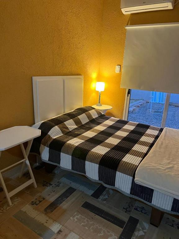 1 dormitorio con cama, lámpara y ventana en Alquiler x dia en Aldea Camarero