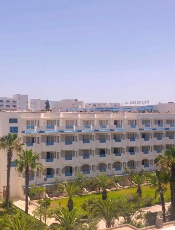 un gran edificio blanco con palmeras delante en Appartement S+2 vue mer 20 mètres pieds dans l'eau, en Port El Kantaoui