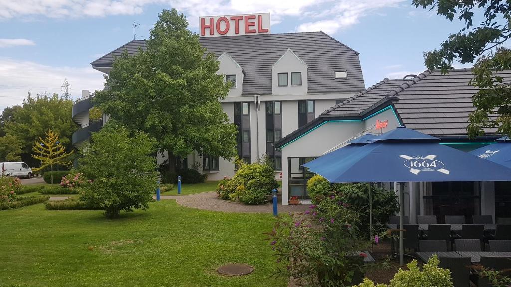 un hôtel avec un parapluie bleu devant lui dans l'établissement Hotel Restaurant La Tour Romaine - Haguenau - Strasbourg Nord, à Schweighouse-sur-Moder
