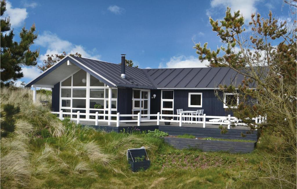 een zwart huis met een witte veranda op een strand bij Lovely Home In Henne With House A Panoramic View in Henne Strand