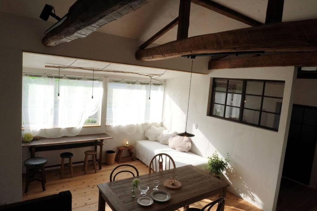 a living room with a white couch and a table at 古民家ここにわ はなれの宿 in Furano