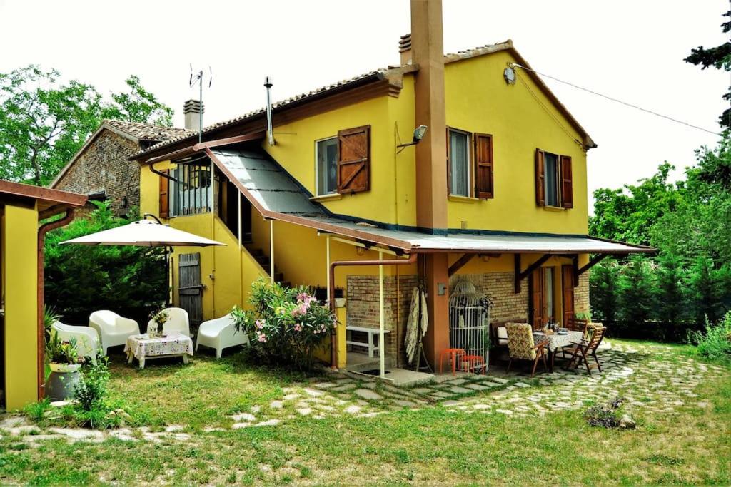 Casa amarilla con sillas y sombrilla en Casa Fiorenza, en Montefelcino
