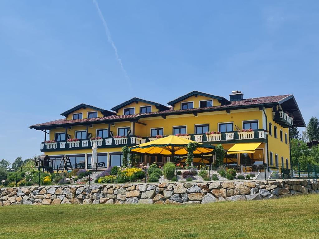 a large yellow building with a stone wall at Landgasthof Entenwirt Tarsdorf in Tarsdorf