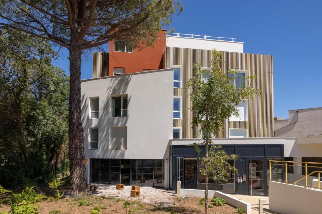 un edificio con un árbol delante de él en Apparteo Montpellier, en Montpellier