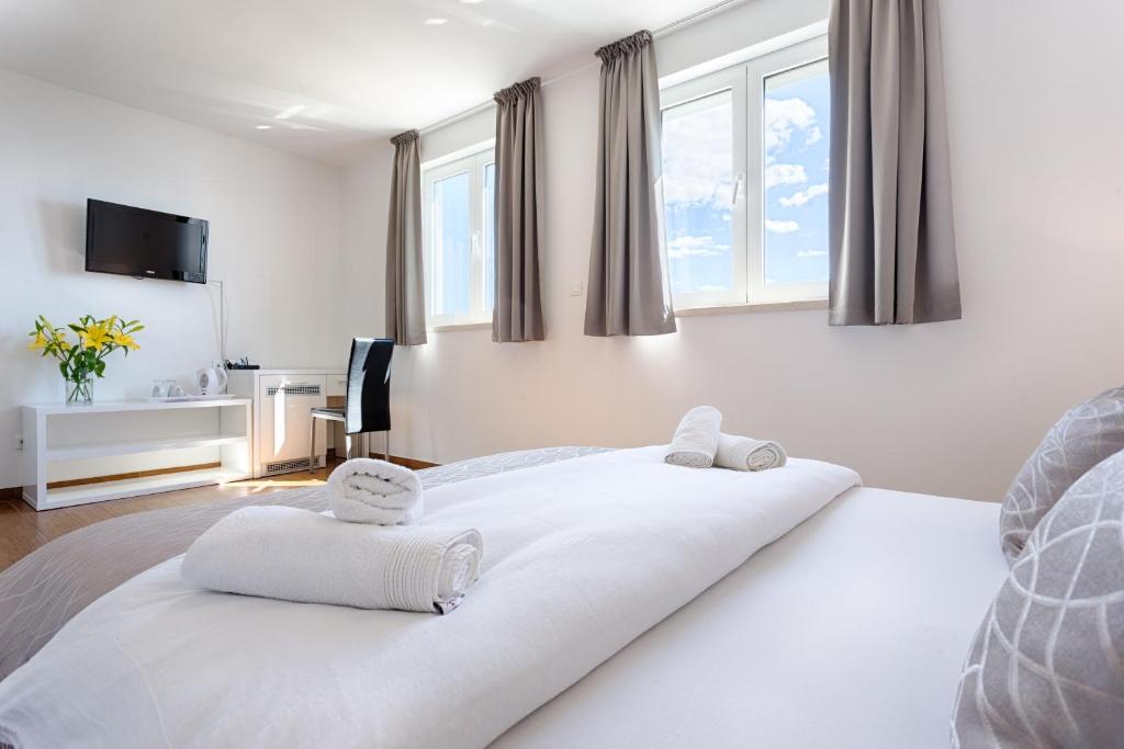 a bedroom with a large white bed with windows at Adriatic Queen Residence in Split