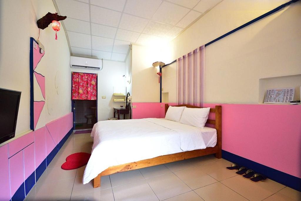 1 dormitorio con 1 cama con paredes rosas y moradas en Ting Yi B & B, en Taitung