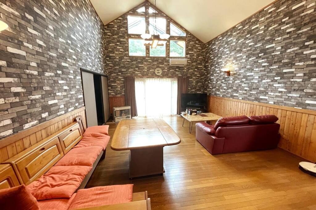 a living room with a couch and a table in a room at 【ウポポイ近く】庭付きログハウステイスト・ BBQセットあり 4名様まで同一料金 in Shiraoi