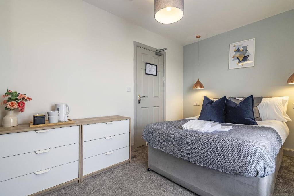 um quarto com uma cama com almofadas azuis e uma cómoda em Stay @ Baker Street Derby em Derby