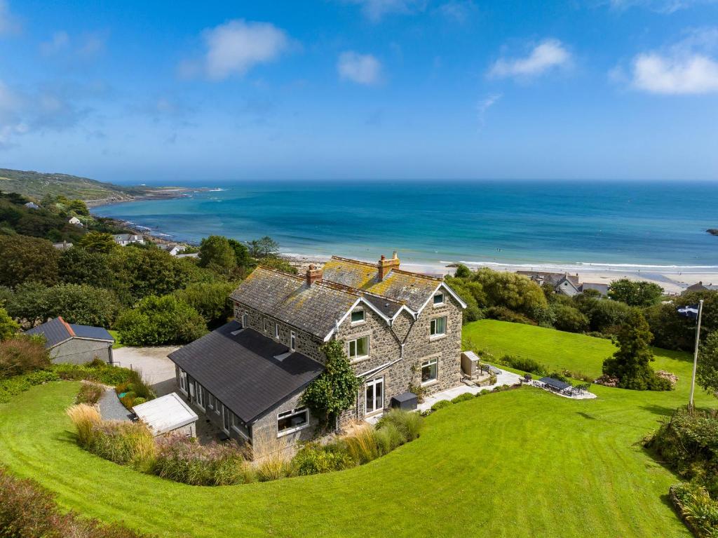 an aerial view of a house on a hill with the ocean at Penmarth House in Helston