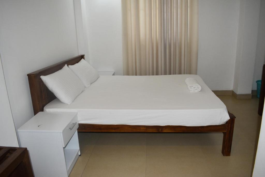 1 dormitorio pequeño con 1 cama con sábanas blancas en Orchard Home en Kandy