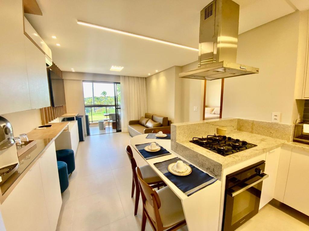 a kitchen and living room with a stove top oven at Flat luxo torre 07 Eco Resort Praia dos Carneiros in Tamandaré