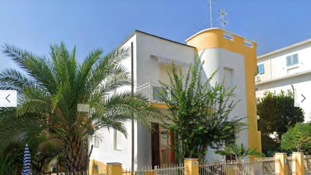 a white building with palm trees in front of it at Villa al mare in Senigallia