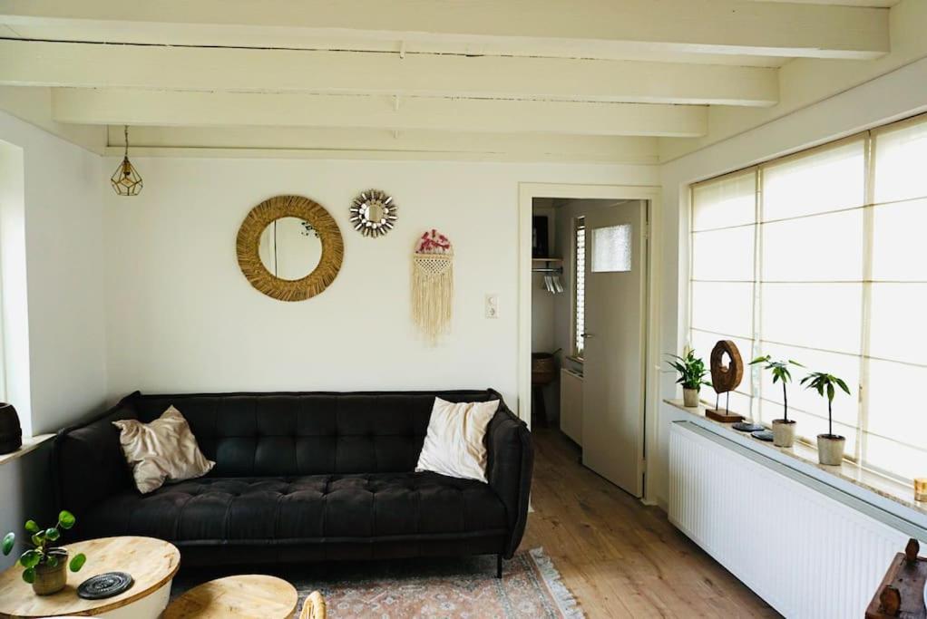 uma sala de estar com um sofá preto e uma mesa em Tiny House Noordwijk aan Zee em Noordwijk