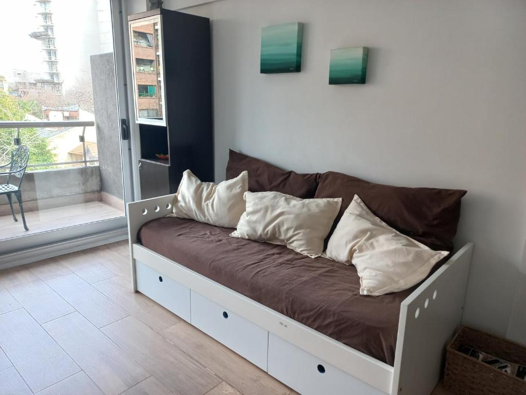 un sofá con almohadas en una habitación en DEPTO NUEVO CON PILETA EN NUÑEZ en Buenos Aires