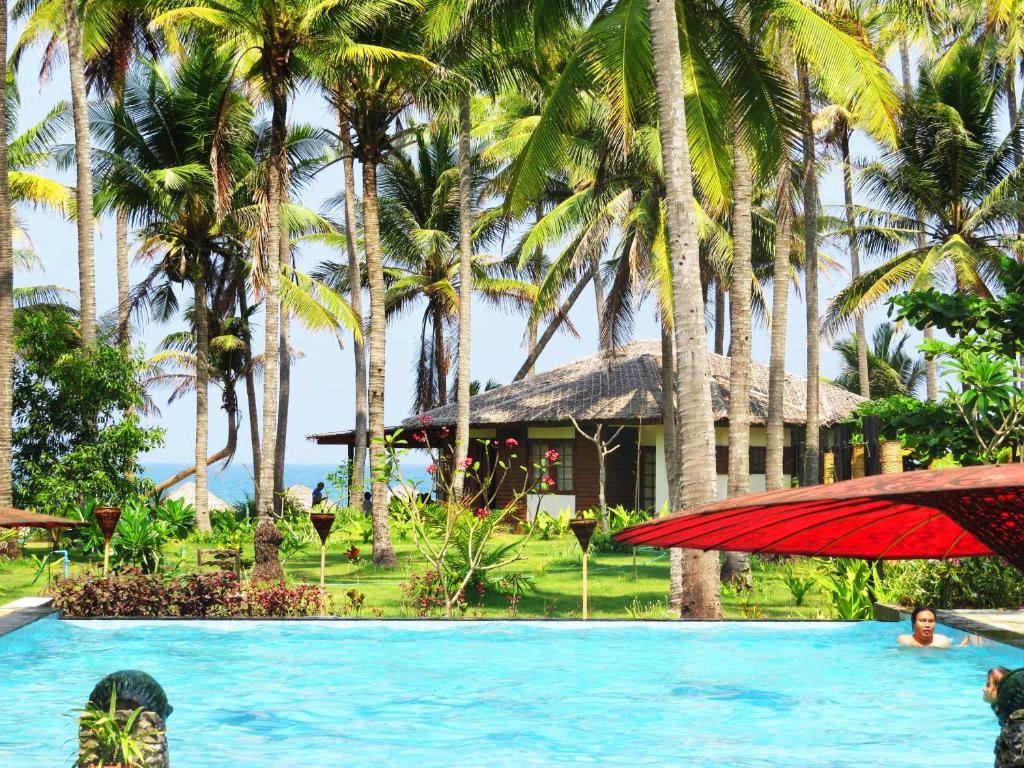 a person in a swimming pool in front of a resort at Emerald Sea Resort in Ngwesaung